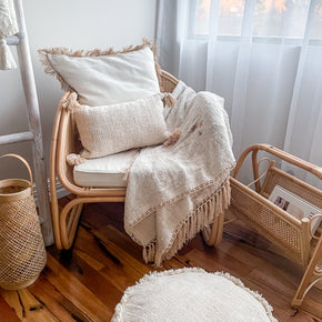 Rattan chair with cushions and a blanket in a cozy room and rattan magazine rack 